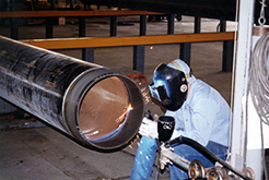 A man welding a pipe at a Dril-Quip Houston facility