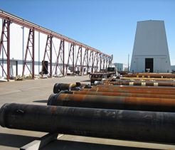 A series of large rusted pipes lined up outside of a Houston Dril-Quip warehouse