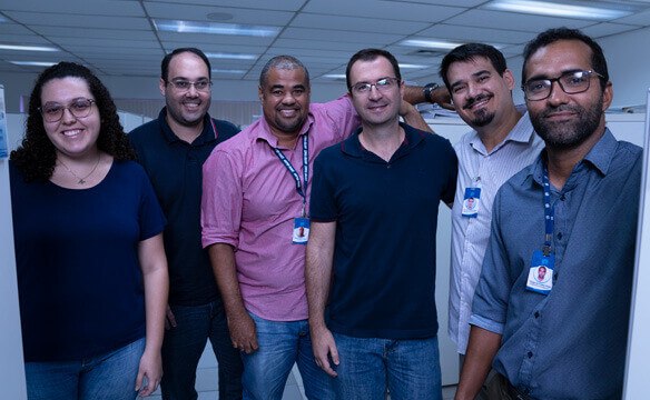 A diverse group of Dril-Quip employees standing around cubicles