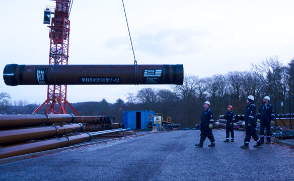 A length of pipe being moved into storage by Dril-Quip employees